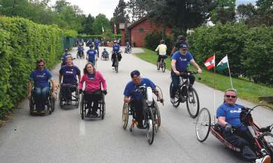Eine Gruppe Rollstuhl- und Radfahrer rollt gemeinsam durch die Umwelt.