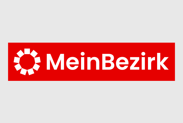 Logo von MeinBezirk.at, einem österreichischen Nachrichtenportal, auf rotem Hintergrund.